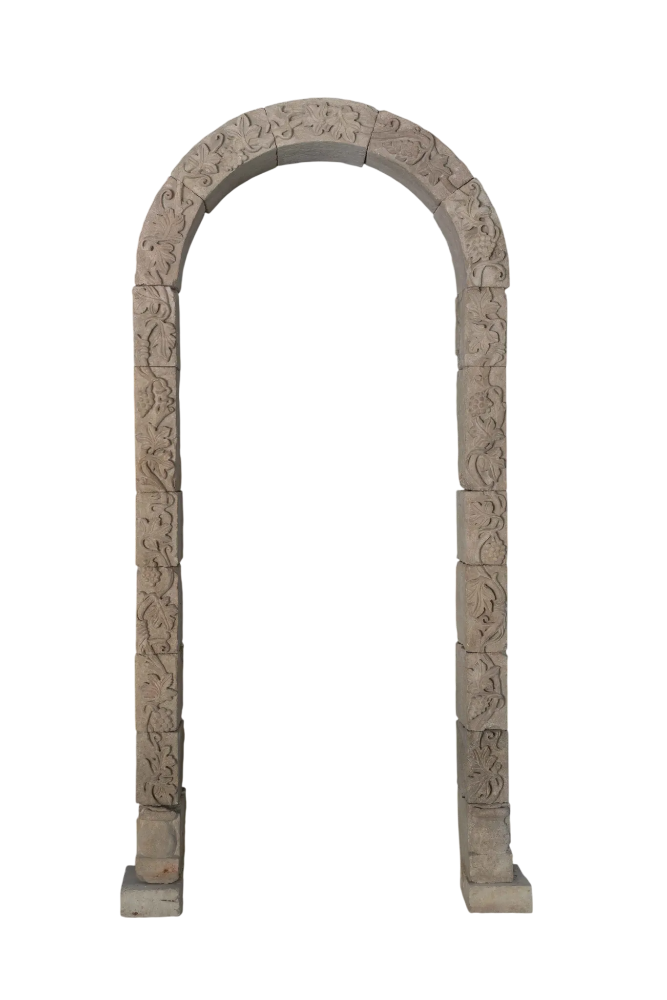 Tall reclaimed antique limestone entryway from Ancient Surfaces with floral carving across its rounded arch and slender stone jambs