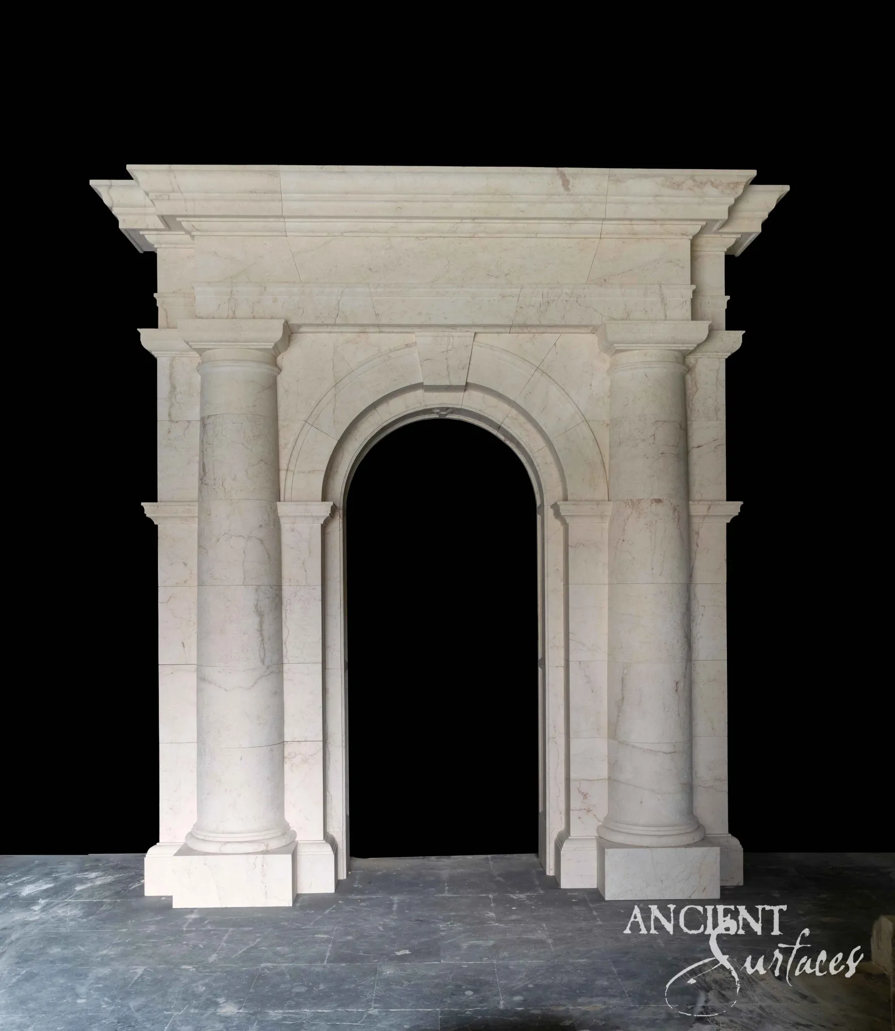 Reclaimed antique limestone entryway from Ancient Surfaces with finely polished engaged round columns and a stepped cornice, photographed on a dark slate floor